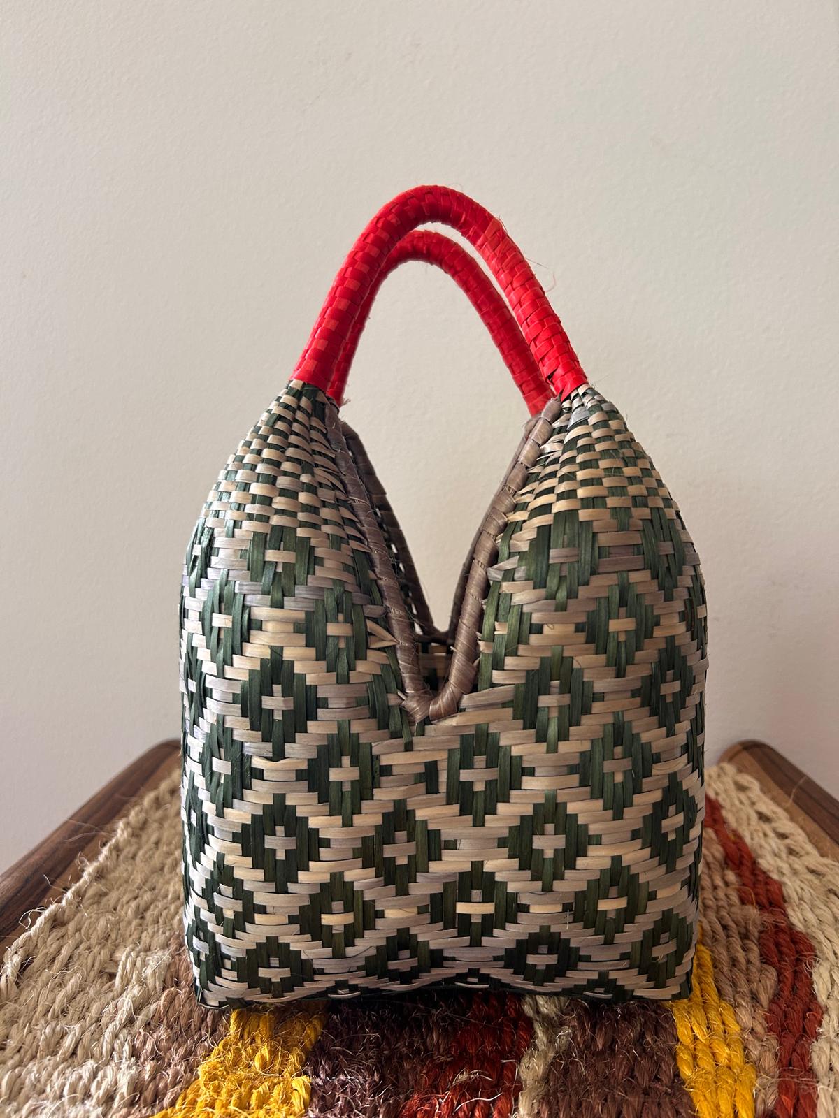 Bolso "Brunita" verde con asa roja y fondo grisáceo
